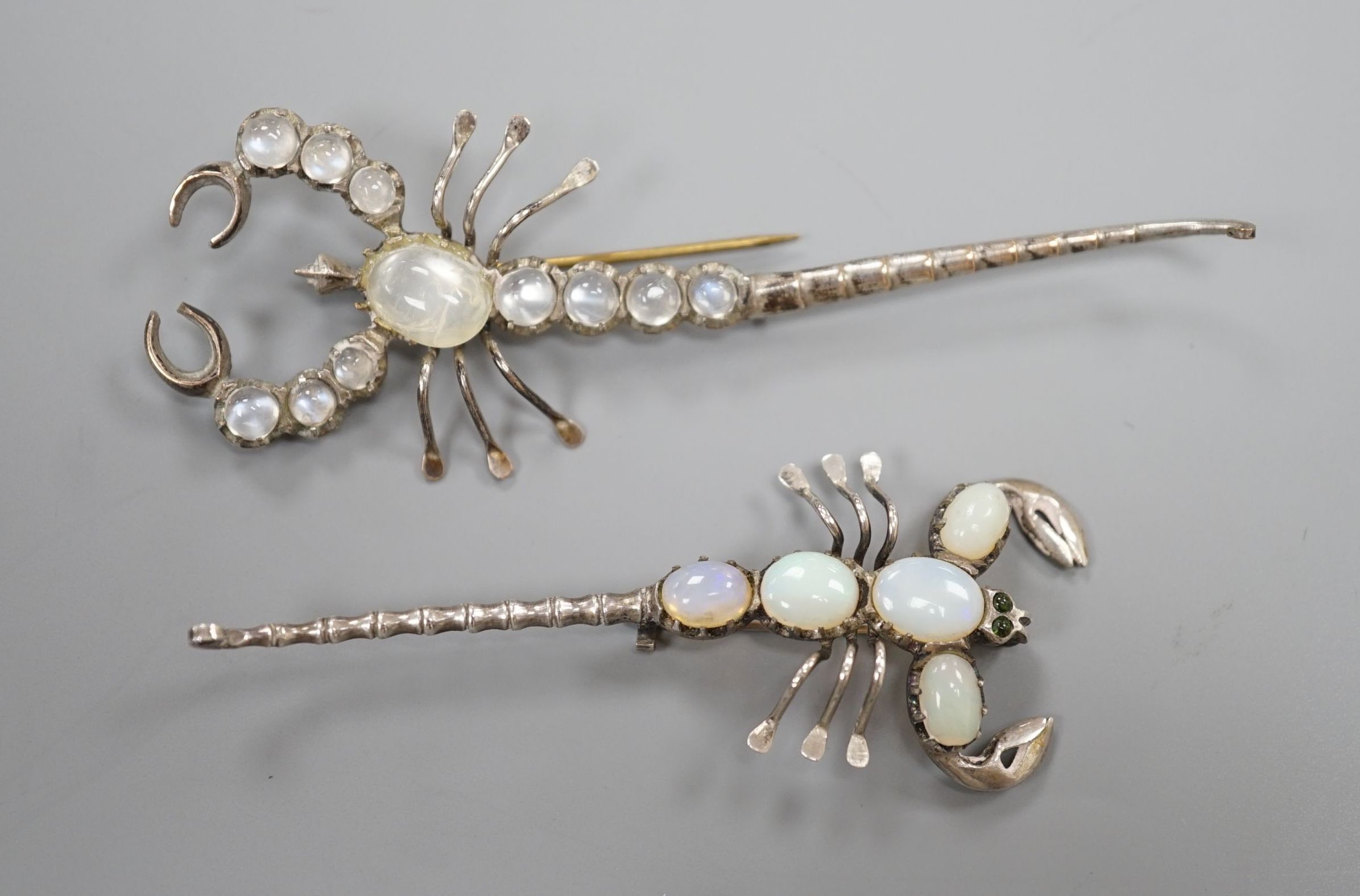 Two white metal scorpion brooches, one set with moonstones, the other with opals, largest 9cm.